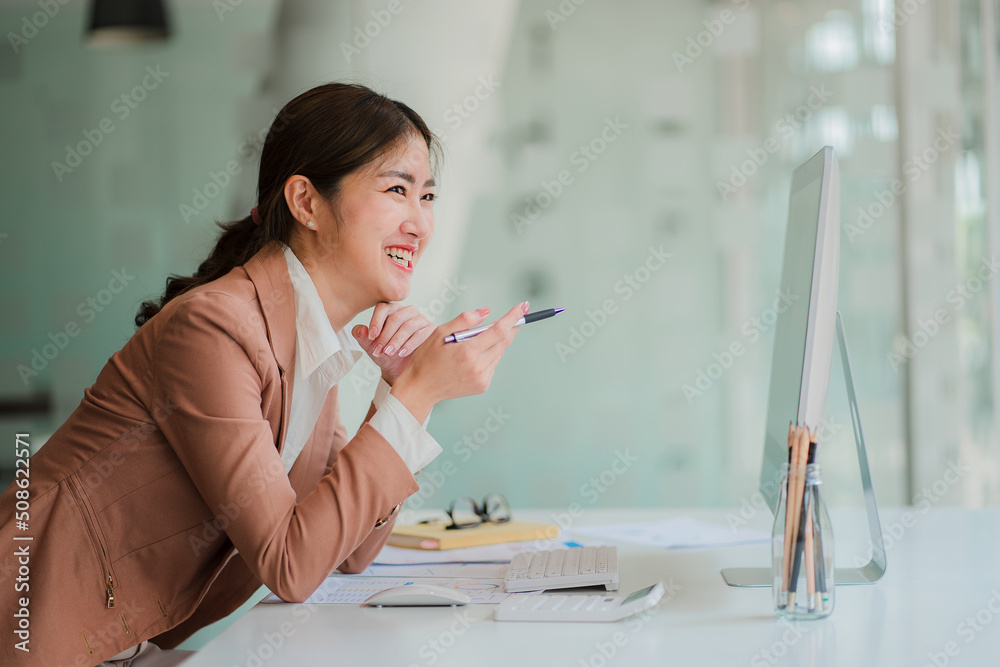 Attractive Asian businesswoman sitting on a computer in the office Prepare a report on the calculation of the amount in the documents of the Internal Revenue Service Attractive Asian businesswoman sitting on a computer in the office Prepare a report on the calculation of the amount in the documents of the Internal Revenue Service