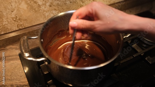 Fotografering Woman mixing smooth delicious dark chocolate ganache with whisk in silver bow