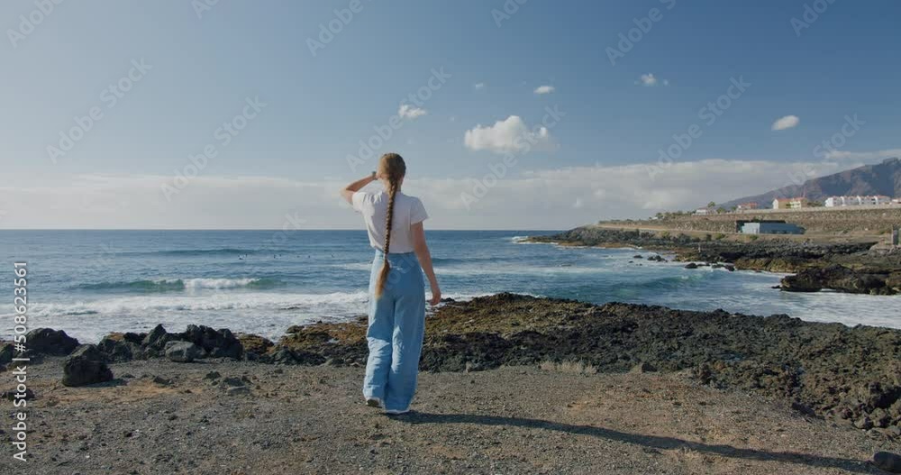 Young woman enjoying the view of the Atlantic Ocean. Volcanic coastline, Puerto de Santiago, Santiago del Teide, Tenerife Young woman enjoying the view of the Atlantic Ocean. Volcanic coastline, Puerto de Santiago, Santiago del Teide, Tenerife