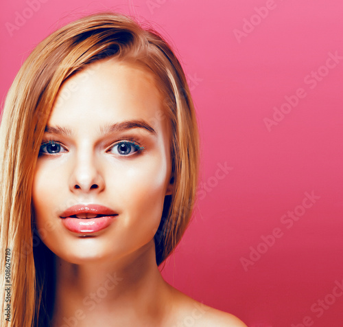 young pretty blonde real woman with hairstyle close up and makeup on pink background smiling