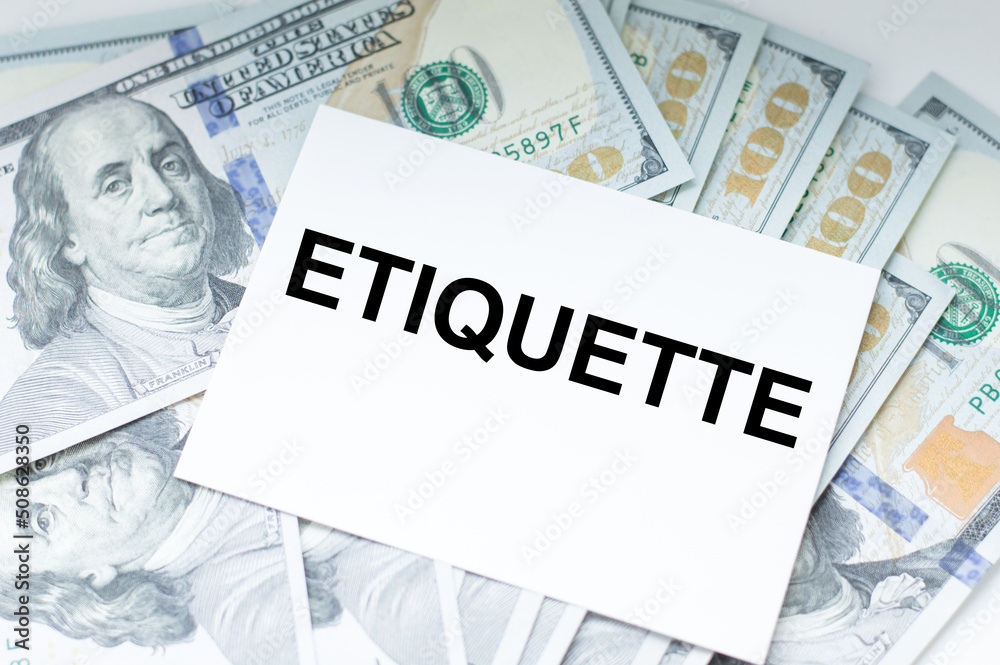 A white business card with ETIQUETTE text on dollar bills background, business concept A white business card with ETIQUETTE text on dollar bills background, business concept