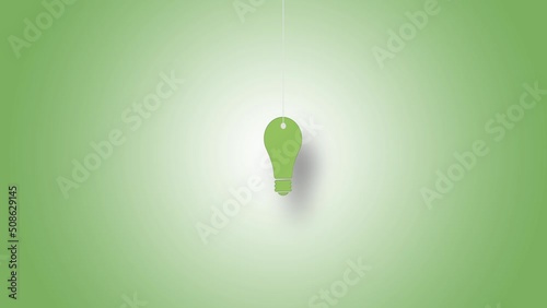 Light bulb symbol in green hanged with strings against green background. High quality video in 4K resolution.
