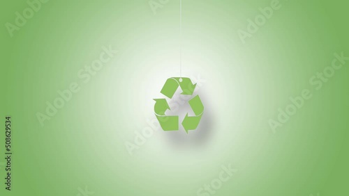 Recycling symbol in green hanged with strings against green background. High quality video in 4K resolution.