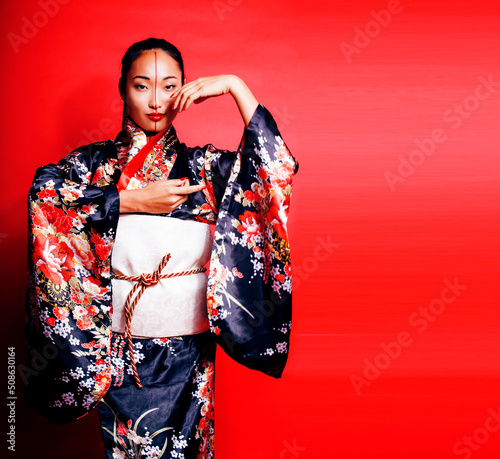 Murais de parede young pretty geisha on red background posing in kimono, oriental