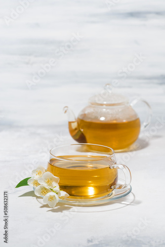 glass cup and teapot with jasmine green tea on a white background, vertical
