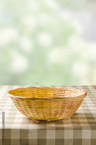 A table with a napkin and a wicker basket for food. Blurry summer or spring background