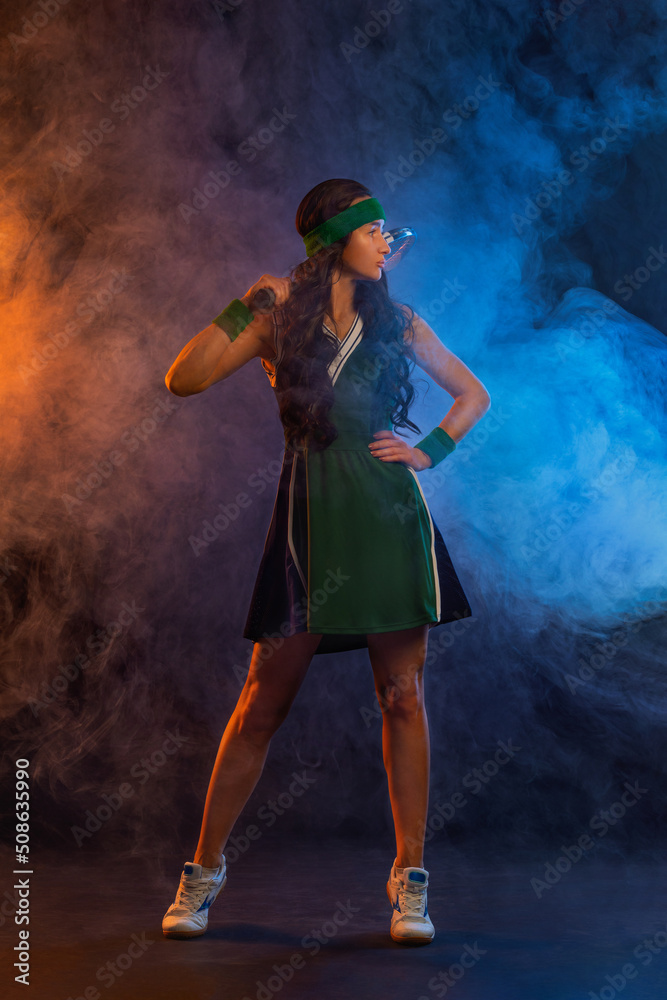 Obraz premium Tennis player with racket in sportswear. Woman athlete playing dark background.