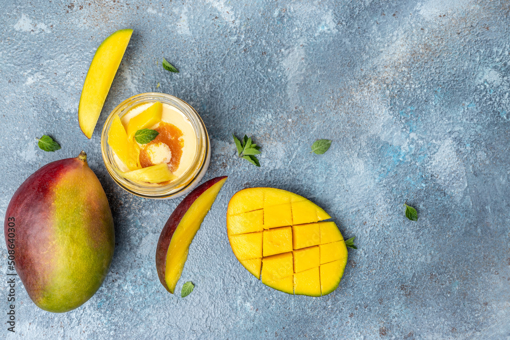 Homemade mango ice cream in a glass jar fresh fruits over blue background. place for text, top view