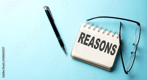 REASONS text written on a notepad on the blue background photo