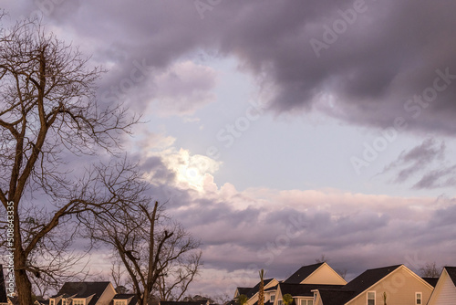 A dark and gloomy sky before a rainstorm with the sun peeking out over a new constuction neighborhood