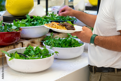 A man chooses a salad from the fresh herb salad bar at the hotel's buffet. healthy food concept