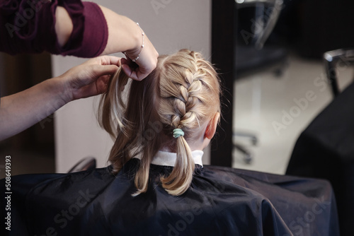 Foto Barber woman make fashionable pretty hairstyle for cute little girl