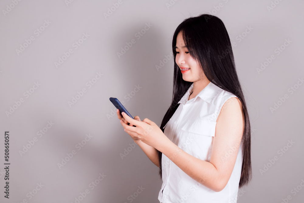 Portrait of smiling asian woman using a smartphone on gray background Portrait of smiling asian woman using a smartphone on gray background