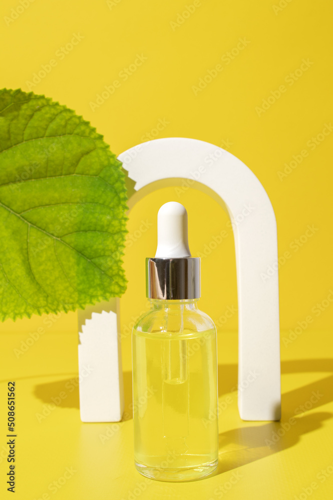 Mock up glass dropper bottle in arch on yellow background with leaves. Hard shadows. Cosmetic facial skin care and spa. Natural treatment concept. Mock up glass dropper bottle in arch on yellow background with leaves. Hard shadows. Cosmetic facial skin care and spa. Natural treatment concept.