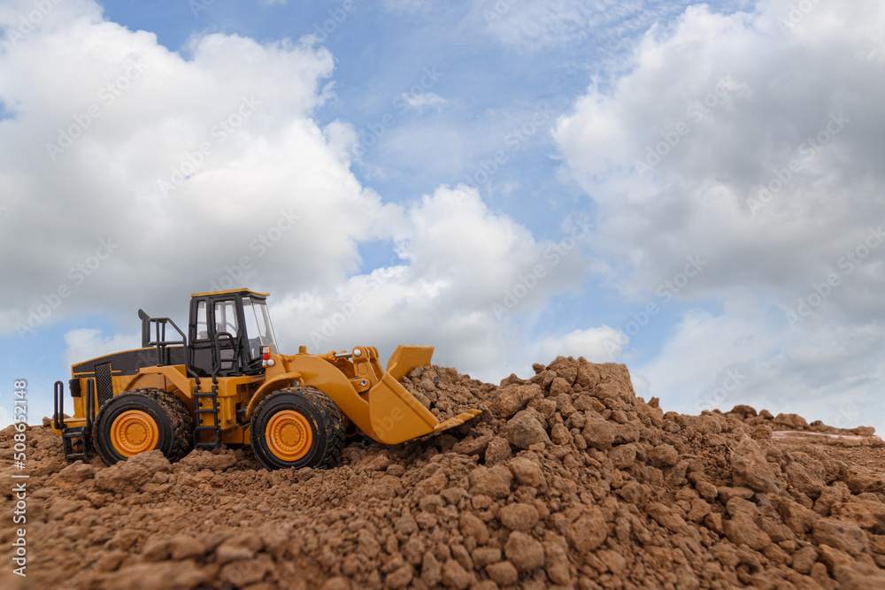 Wheel loader are digging the soil in the construction site on sky background ,with white fluffy cloud Wheel loader are digging the soil in the construction site on sky background ,with white fluffy cloud