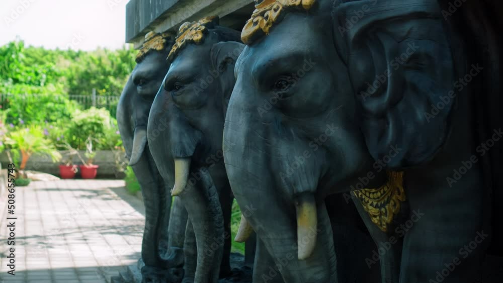 Statues of elephants holding a concrete slab on their backs