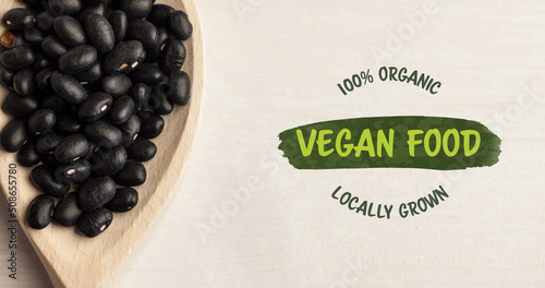 Image of vegan food text in green over fresh organic black beans in wooden bowl