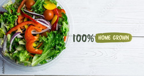 Image of 100 percent home grown text in green over fresh organic vegetable salad in bowl on wood