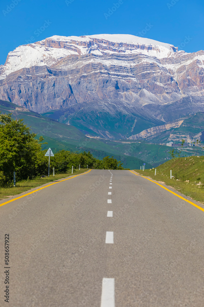 Asphalt road leading to snowy mountains