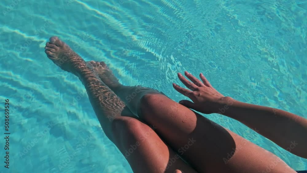 Slim tanned legs and feet of young female model in public pool in the spa.