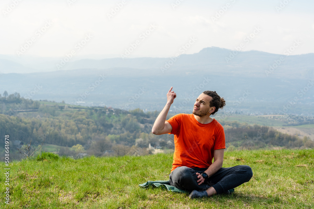 Man sitting on the mountain peak and telling something