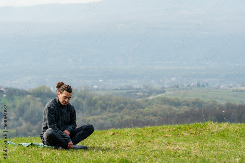Young man sitting on the mountain peak Young man sitting on the mountain peak