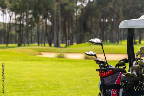 Set of golf clubs in golf bags in the back of a golf cart on a beautiful golf course photo