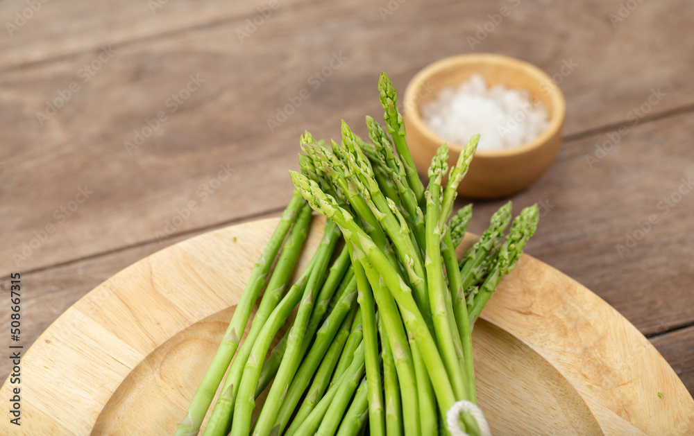 Asparagus is green and straight vegetable. Fresh, green asparagus is crispy for cook on wood table with salt Asparagus is green and straight vegetable. Fresh, green asparagus is crispy for cook on wood table with salt