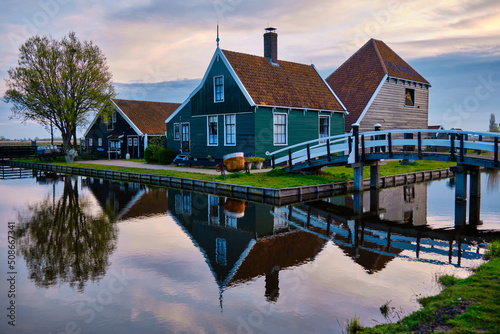 April 13 2022, Zaanse Schans, Netherlands, Authentic wooden Dutch houses on the banks of the river Zaan. Reflections in the water.