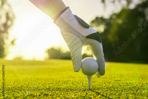 Closeup of golfer wearing glove placing golf ball on a tee at golf course
