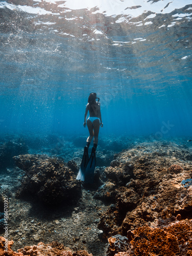 Woman in bikini with freediving fins underwater in ocean at Oahu island