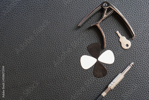 Objects to play guitar on leather surface, guitar plectrum, guitar capo, jack cable photo