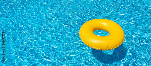 Yellow inflatable ring floating in swimming pool. Vacation concept with copy space