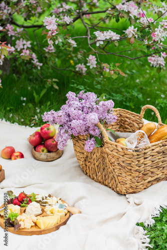 Breakfast picnic with at spring blossom garden on a white tablecloth on a sunny day, cherry blossoms. Outdoor, picnic, brunch, spring mood
