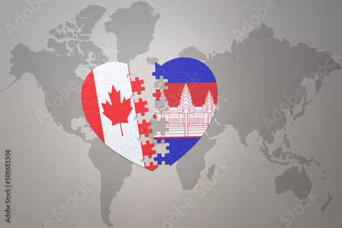 puzzle heart with the national flag of canada and cambodia on a world map background.Concept.