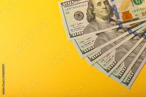 Money, US hundred dollar banknotes background on yellow background. Money is scattered on the table. Concepts of finance and economy. Money accumulation concept. Saving currency. Investments. 