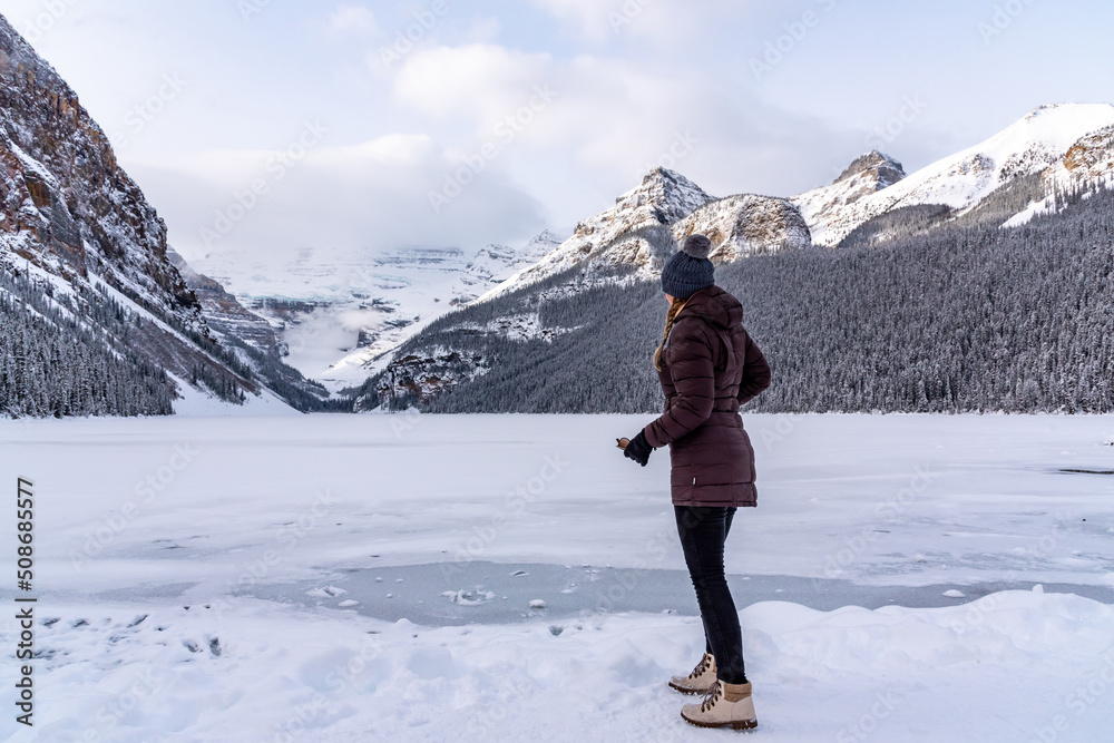 Lake Louise, Alberta, Canada - Woman tourist standing beside the stunning tourist area in winter time. 