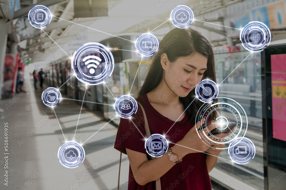 Asian woman passenger suit using the smart mobile phone over Wireless communication connecting of smart city Internet of Things Technology in the BTS Skytrain rails or MRT subway, lifestyle concept