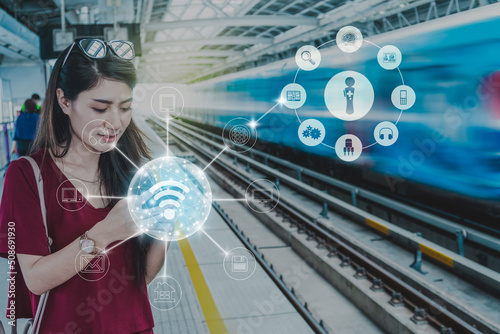 Obraz na płótnie Asian woman passenger with casual suit using the social network via smart mobile phone in the Skytrain rails or MRT subway for online shopping with omni channel, lifestyle and transportation concept w salonie