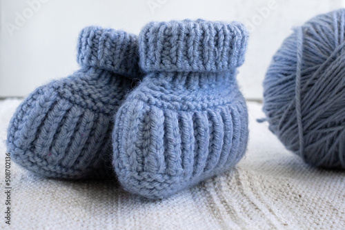Knitted socks for newborns and ball of thread. Concept of handmade knitted clothes for babies.  © Aisylu