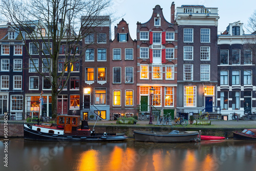 Beautiful old houses on the city waterfront of Amsterdam at sunset.