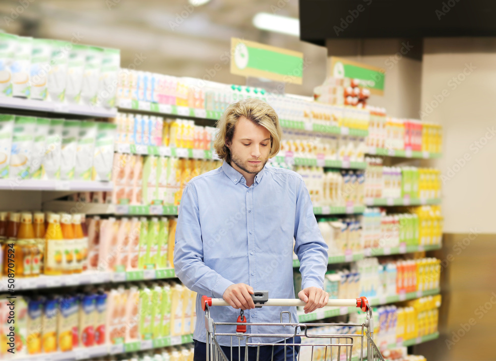 Young man choosing a dairy products at supermarket, reading product information
