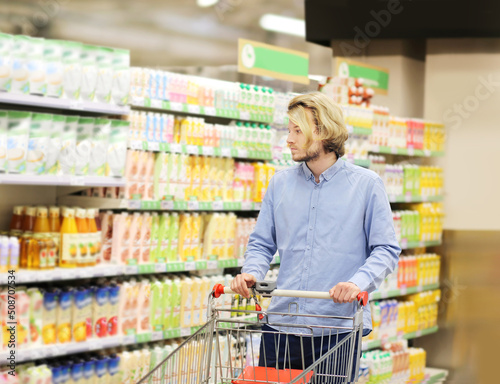 Young man choosing a dairy products at supermarket, reading product information