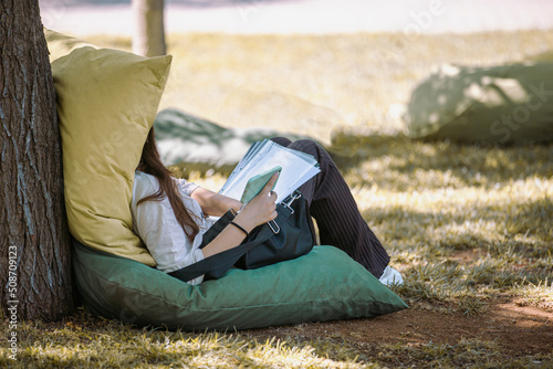 Student studying on lawn and cushions in university garden