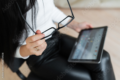 A young business girl solves problems online on a tablet. Young woman chatting on a virtual online conference. The concept of communication is not in the office, online work.