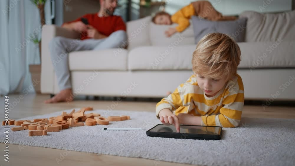 Little boy lying on floor and using tablet at home Little boy lying on floor and using tablet at home