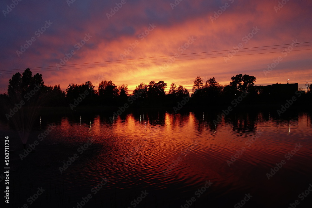 Sunset in orange tones with reflection in water and line of trees