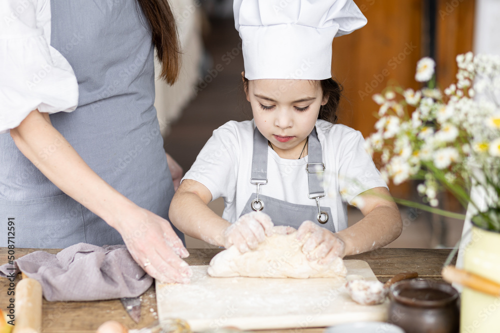 Mother and daughter baking homemade sweet pie together, having fun. Home bakery, family time, little kids in process of food preparation in the kitchen at home, helping mother, doing chores Mother and daughter baking homemade sweet pie together, having fun. Home bakery, family time, little kids in process of food preparation in the kitchen at home, helping mother, doing chores