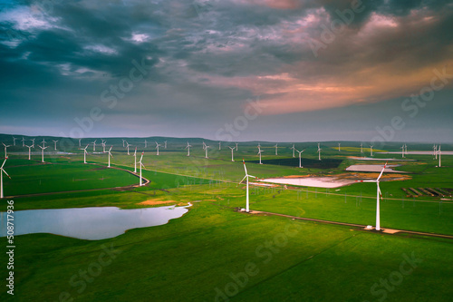 Wind turbine farm at sunset. Renewable energy concept. Producing alernative energy in windmills photo