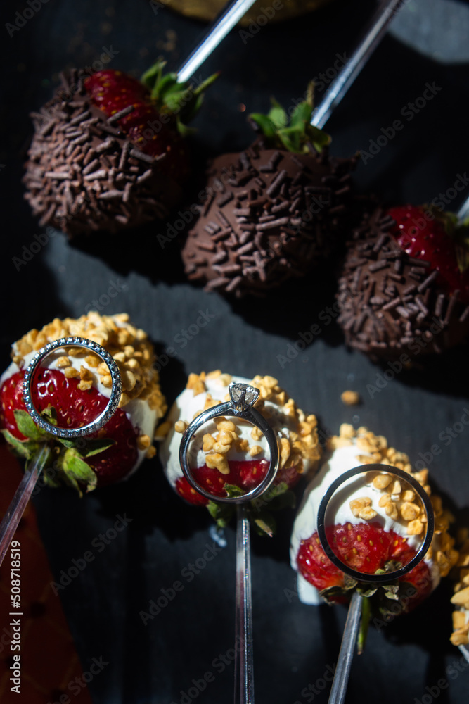 Fototapeta premium Three wedding rings lie on strawberry desserts
